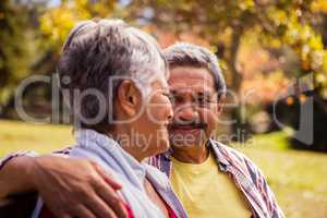 Elderly couple looking at each other while sitting on a bench