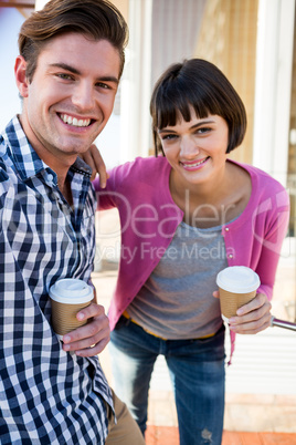 Happy couple with coffee cups looking at camera