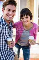 Happy couple with coffee cups looking at camera