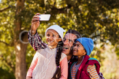 Cheerful father taking selfie with children