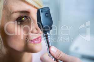 Optometrist examining female patient through ophthalmoscope