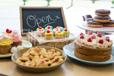 Close-up of various sweet foods on table with open signboard