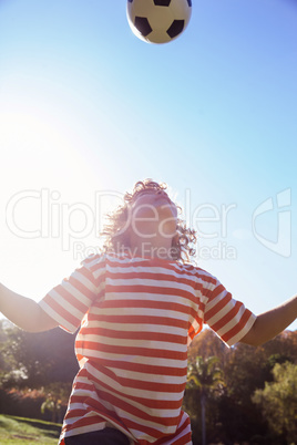 Low angle view of boy playing with soccer ball in park