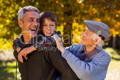 Happy man piggybacking son while with father at park