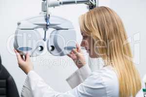 Attentive female optometrist adjusting phoropter