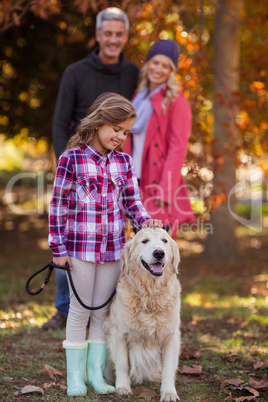 Girl stroking dog while parents at park
