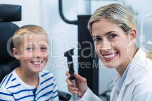 Female optometrist examining young patient with ophthalmoscope