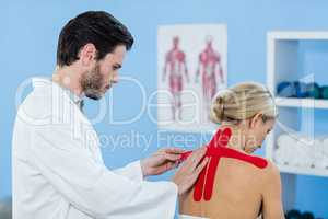 Physiotherapist sticking tape on female patient