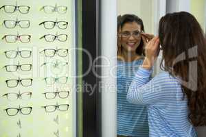 Female customer wearing spectacles and checking in mirror