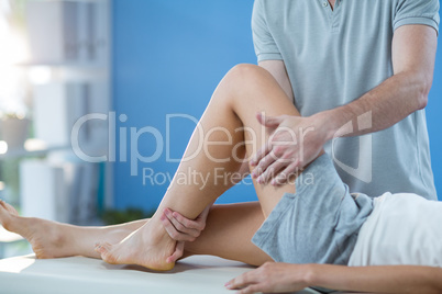 Male physiotherapist giving knee massage to female patient