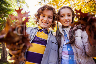 Low angle portrait of siblings showing autumn leaves