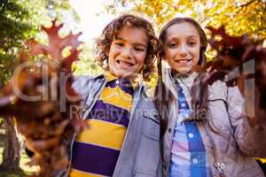 Low angle portrait of siblings showing autumn leaves
