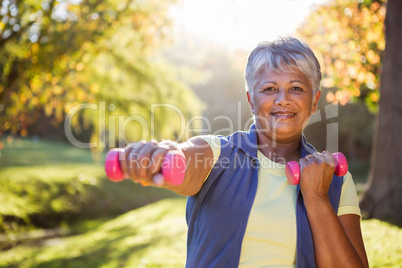 Smiling mature woman exercising with dumbbell