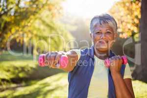 Smiling mature woman exercising with dumbbell