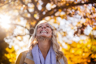 Smiling woman looking up against trees