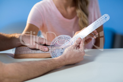 Physiotherapist examining female patients wrist with goniometer