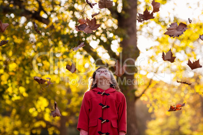 Happy girl standing against tree with autumn fall