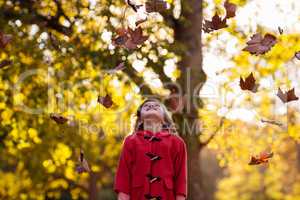 Happy girl standing against tree with autumn fall