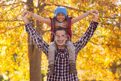 Happy father carrying son on shoulder at park