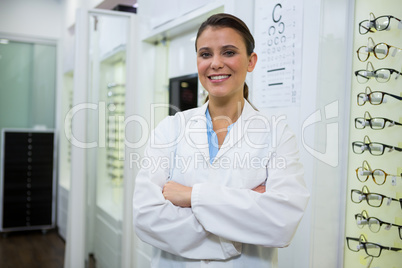 Optometrist standing with arms crossed in optical store