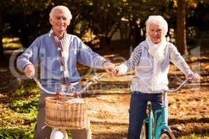 Senior couple riding their bike and holding their hands