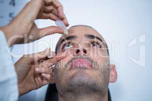 Optometrist putting drops into patients eyes
