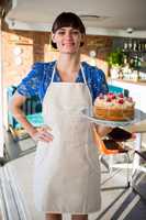 Portrait of smiling waitress holding a cake