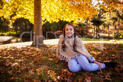 Portrait of smiling girl sitting at park during autumn