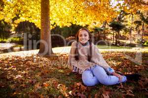 Portrait of smiling girl sitting at park during autumn