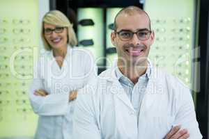 Smiling optometrists standing with arms crossed