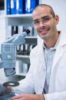 Smiling male optometrist with microscope