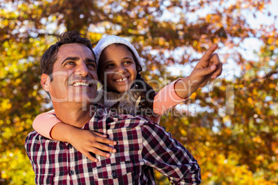 Daughter gesturing while piggybacking with father at park