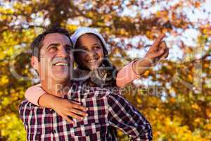 Daughter gesturing while piggybacking with father at park