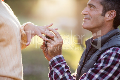 Smiling man putting ring in woman hand