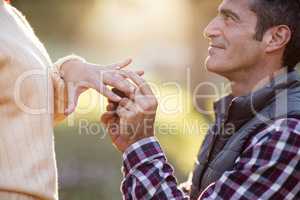 Smiling man putting ring in woman hand
