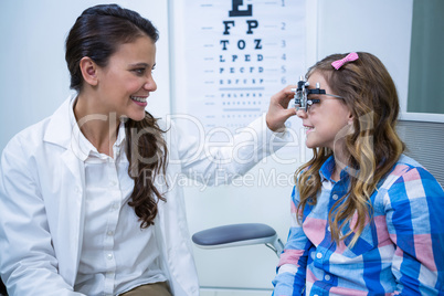 Female optometrist examining young patient with trial frame