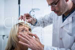 Optometrist putting drops into patients eyes