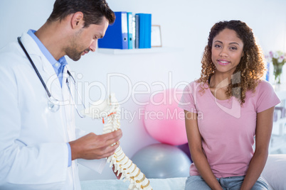 Physiotherapist explaining spine model to patient