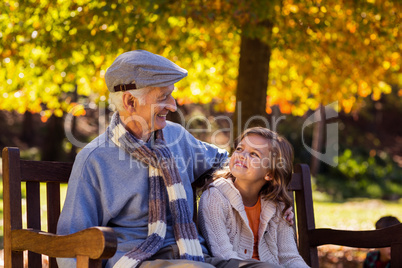 Grandfather sitting with granddaughter at park