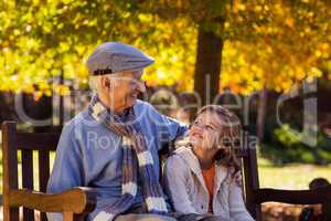 Grandfather sitting with granddaughter at park