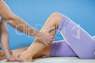 Male physiotherapist giving knee massage to female patient