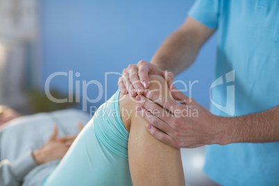 Male physiotherapist giving knee massage to female patient