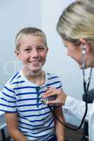 Female doctor examining young patient with a stethoscope