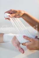 Physiotherapist putting bandage on male patient hand