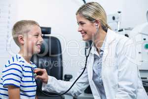 Female optometrist examining young patient with a stethoscope