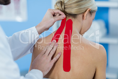 Physiotherapist sticking tape on female patient