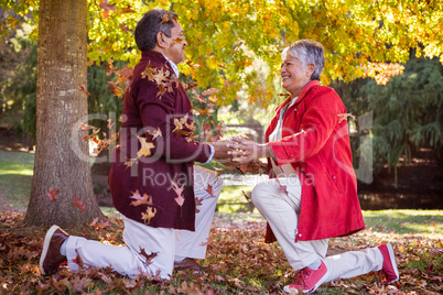 Mature couple kneeling on autumn leaves