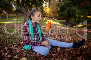 Girl blowing pinwheel in park during autumn