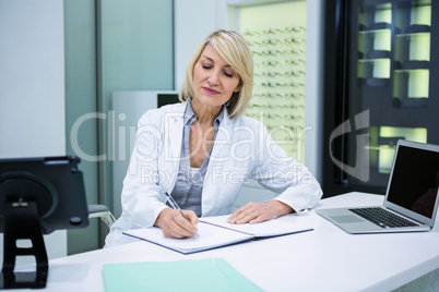 Optometrist writing in book at ophthalmology clinic