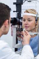 Optometrist examining female patient on slit lamp